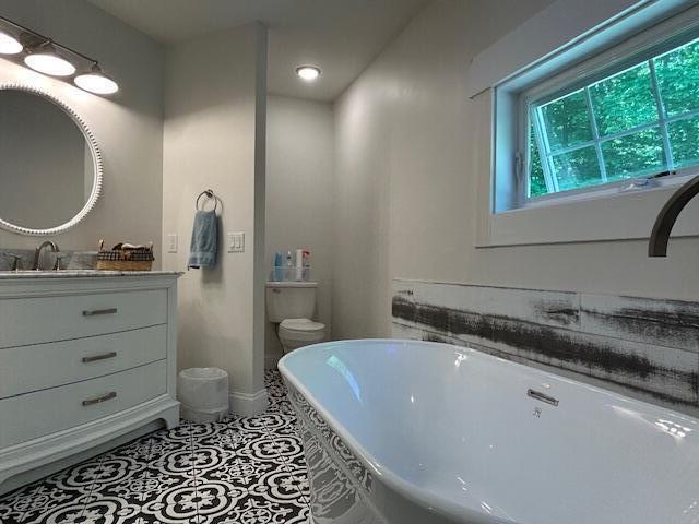 453 Canton Rd, Livermore, ME 04253 - bathroom with a freestanding bath, vanity, baseboards, toilet, and recessed lighting