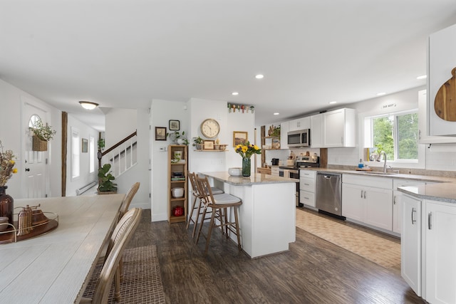 140 New Meadows Rd, West Bath, ME 04530 - kitchen featuring appliances with stainless steel finishes, dark wood finished floors, a kitchen breakfast bar, white cabinets, and decorative backsplash