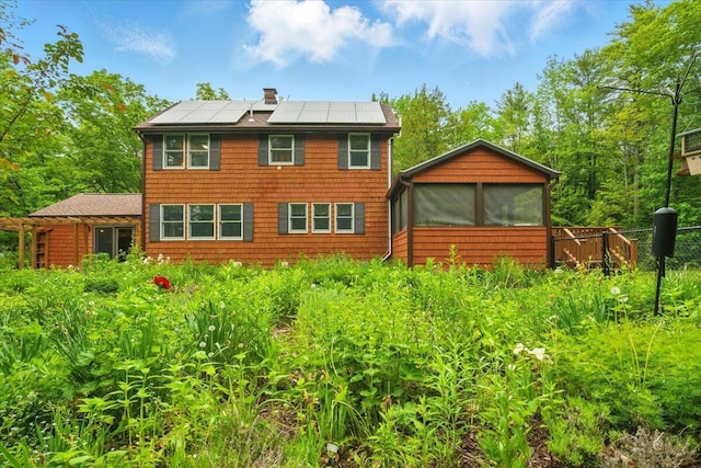 463 Cobbs Bridge Rd, New Gloucester, ME 04260 - rear view of house featuring a sunroom, solar panels, and a chimney