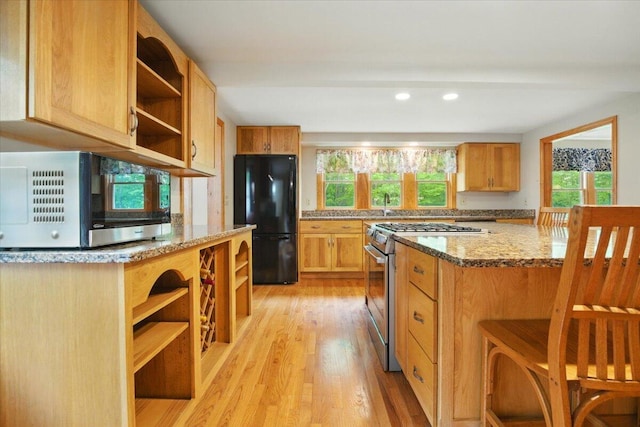 463 Cobbs Bridge Rd, New Gloucester, ME 04260 - kitchen with open shelves, appliances with stainless steel finishes, light wood finished floors, a kitchen bar, and light stone counters
