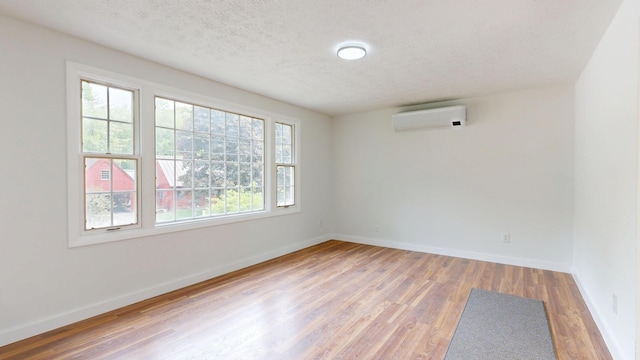 1 Barker St, Jay, ME 04239 - unfurnished room featuring a wall unit AC, wood finished floors, and a textured ceiling