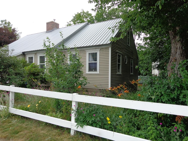 27 Grove St, Sanford, ME 04083 - view of property exterior with a chimney, a metal roof, and a standing seam roof