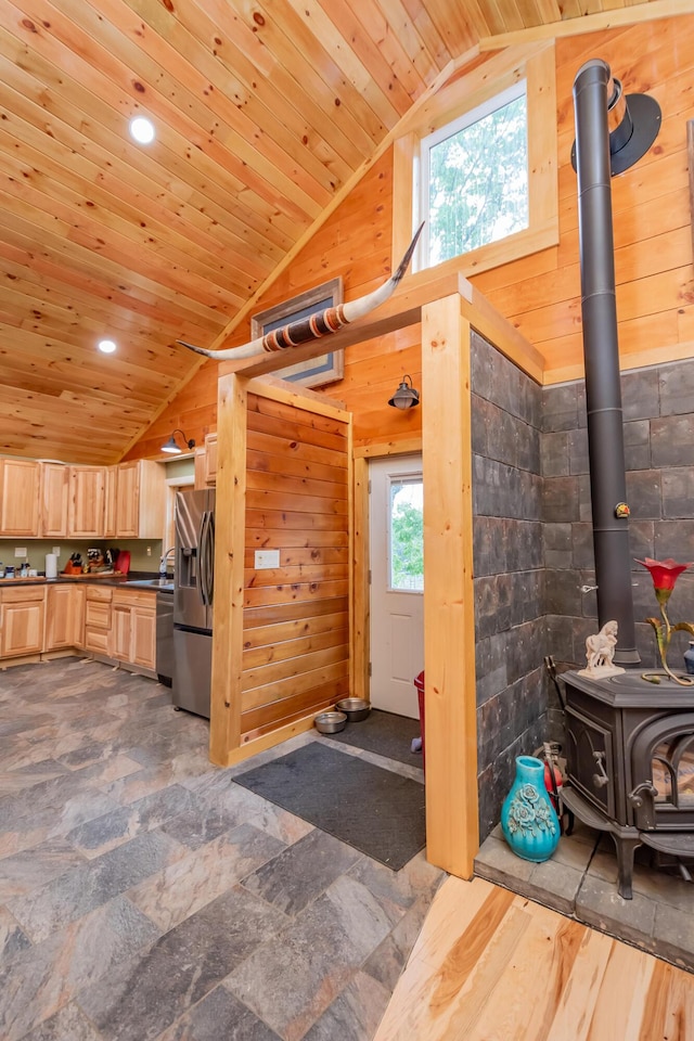54 Carver Rd, Milo, ME 04463 - kitchen with light brown cabinets, stainless steel appliances, wooden walls, wooden ceiling, and a wood stove