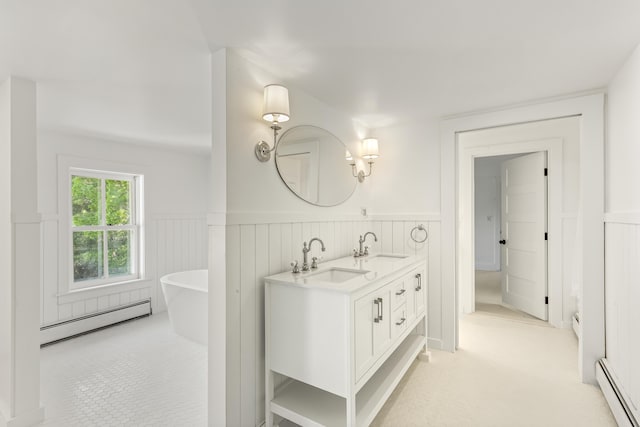 565 Bagaduce Rd, Brooksville, ME 04617 - bathroom with a baseboard radiator, a wainscoted wall, double vanity, and a freestanding tub