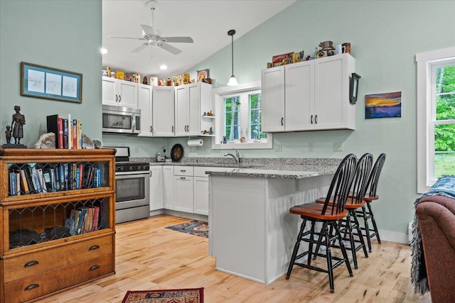489 Shady Nook Rd, Newfield, ME 04095 - kitchen with stainless steel appliances, vaulted ceiling, a peninsula, a kitchen breakfast bar, and light wood-style flooring