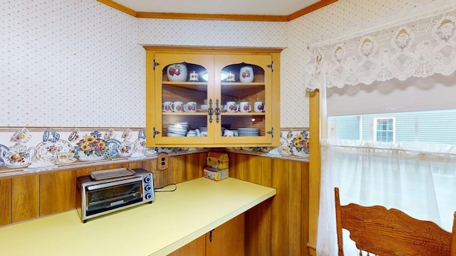 180 Bowdoin St, Millinocket, ME 04462 - kitchen featuring wallpapered walls, crown molding, brown cabinetry, light countertops, and glass insert cabinets