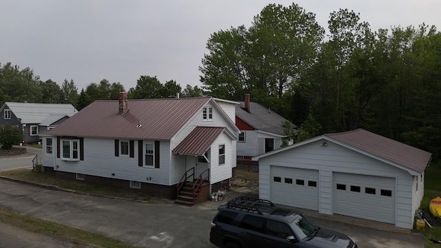 180 Bowdoin St, Millinocket, ME 04462 - view of front of home with a detached garage, an outdoor structure, metal roof, and a chimney