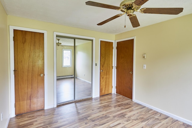 1372 Post Rd Unit 3A, Wells, ME 04090 - unfurnished bedroom featuring light wood-style floors, baseboard heating, baseboards, and two closets