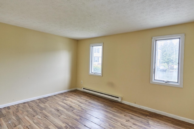 1372 Post Rd Unit 3A, Wells, ME 04090 - unfurnished room featuring baseboard heating, wood finished floors, healthy amount of natural light, baseboards, and a textured ceiling