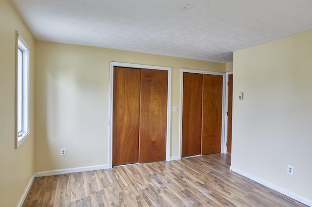 1372 Post Rd Unit 3A, Wells, ME 04090 - unfurnished bedroom with wood finished floors, baseboards, two closets, and a textured ceiling