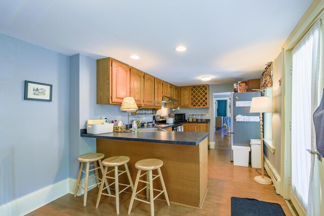 86 High St, Belfast, ME 04915 - kitchen featuring light wood finished floors, a peninsula, dark countertops, stainless steel electric range oven, and brown cabinetry