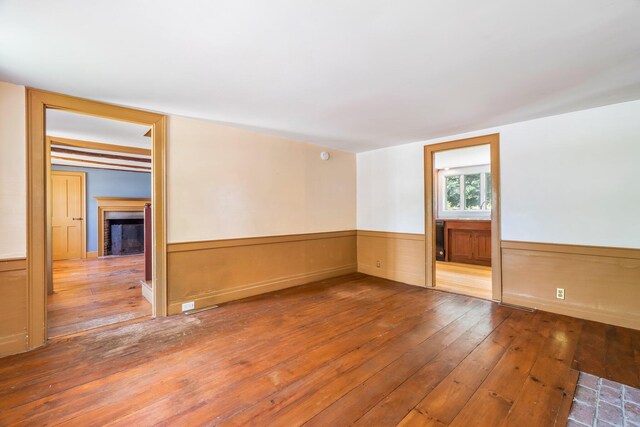 16 Old Village Rd, Winthrop, ME 04364 - unfurnished room with hardwood / wood-style flooring, a wainscoted wall, and a fireplace with flush hearth
