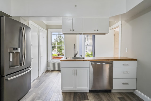 2 Stobie St, Winslow, ME 04901 - kitchen featuring stainless steel appliances, radiator, butcher block counters, white cabinetry, and dark wood-style floors