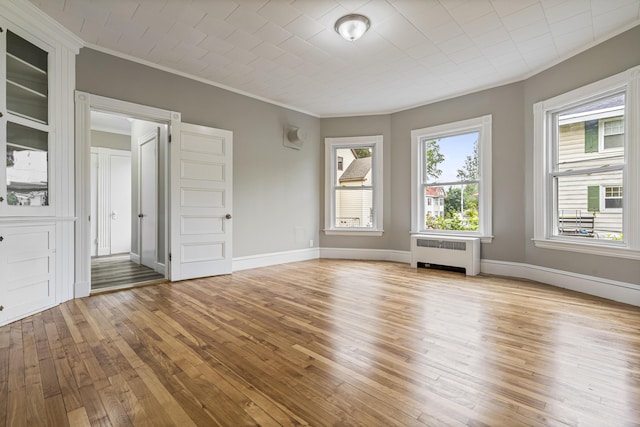 2 Stobie St, Winslow, ME 04901 - empty room with radiator heating unit, crown molding, and light wood finished floors