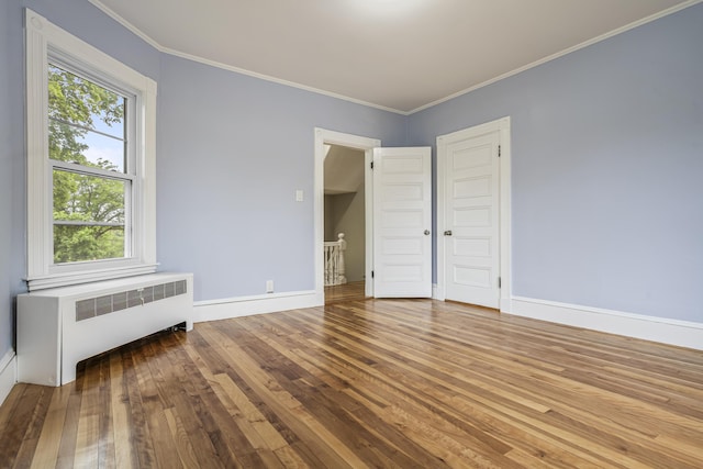 2 Stobie St, Winslow, ME 04901 - unfurnished bedroom featuring radiator heating unit, multiple windows, wood-type flooring, and ornamental molding