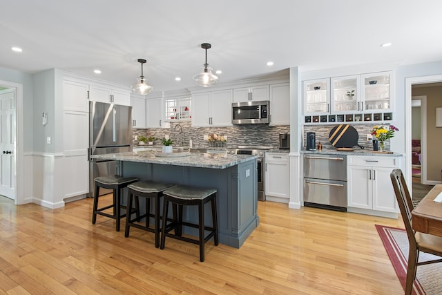 6 Hackmatack Dr, Scarborough, ME 04074 - kitchen with appliances with stainless steel finishes, tasteful backsplash, light wood-style flooring, a breakfast bar area, and white cabinetry