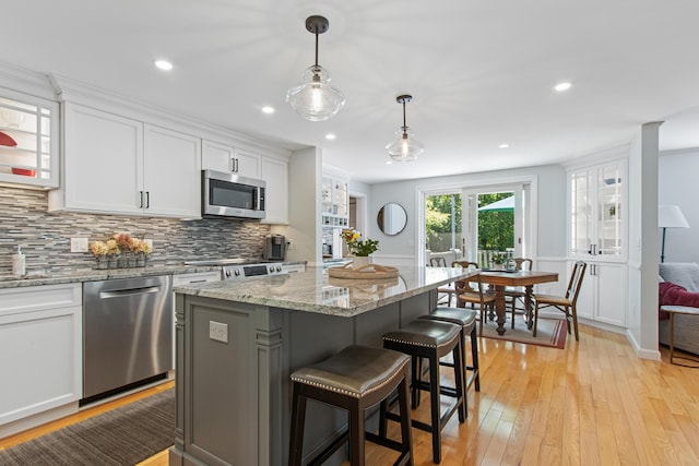 6 Hackmatack Dr, Scarborough, ME 04074 - kitchen with stainless steel appliances, light wood finished floors, white cabinetry, backsplash, and a breakfast bar area