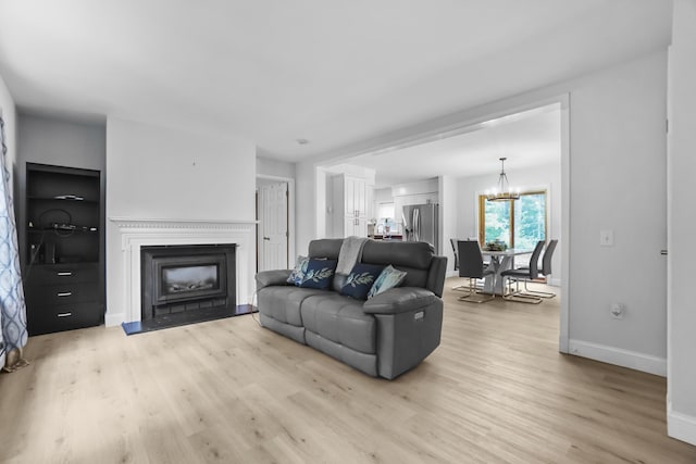 282 Back Narrows Rd, Boothbay, ME 04537 - living room featuring light wood-style flooring, a fireplace, and a chandelier
