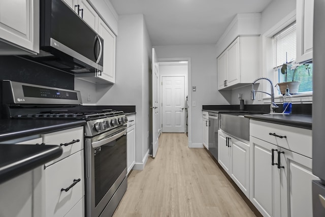 282 Back Narrows Rd, Boothbay, ME 04537 - kitchen with stainless steel appliances, light wood finished floors, white cabinets, and dark countertops