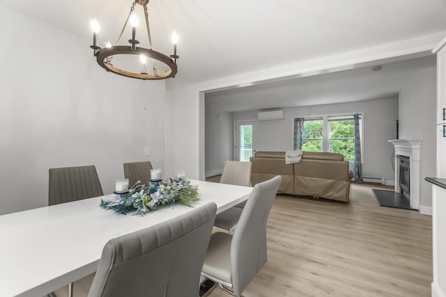 282 Back Narrows Rd, Boothbay, ME 04537 - dining space with a wall unit AC, light wood finished floors, a chandelier, and a fireplace with raised hearth