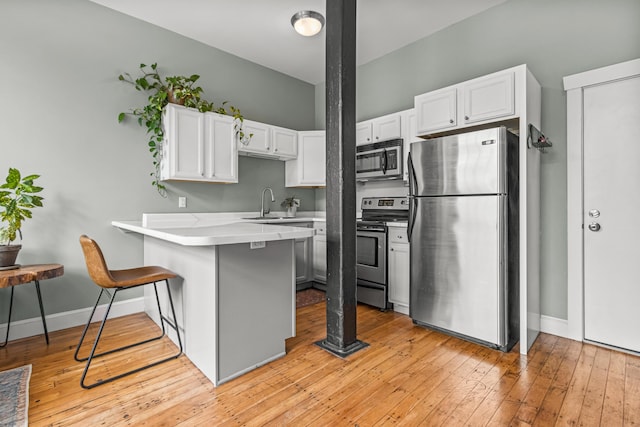 30 Lincoln St Unit 109, Westbrook, ME 04092 - kitchen featuring stainless steel appliances, a peninsula, white cabinetry, a kitchen bar, and light countertops