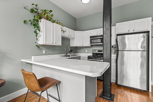 30 Lincoln St Unit 109, Westbrook, ME 04092 - kitchen featuring appliances with stainless steel finishes, a sink, a peninsula, light countertops, and white cabinetry