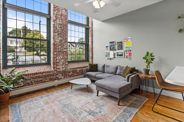 30 Lincoln St Unit 109, Westbrook, ME 04092 - living room with a baseboard heating unit, ceiling fan, brick wall, hardwood / wood-style flooring, and a high ceiling