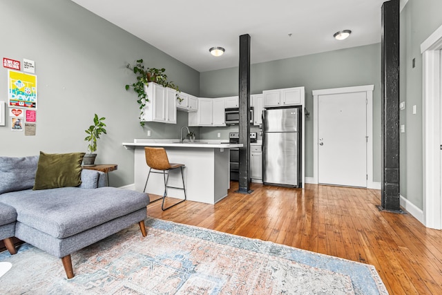 30 Lincoln St Unit 109, Westbrook, ME 04092 - kitchen featuring stainless steel appliances, a peninsula, light countertops, a breakfast bar area, and light wood-type flooring