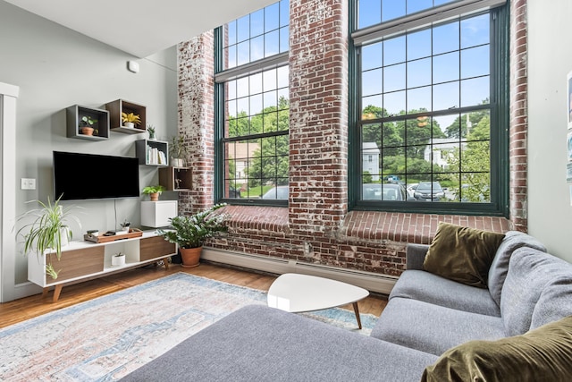 30 Lincoln St Unit 109, Westbrook, ME 04092 - living room with brick wall, a baseboard radiator, wood finished floors, and a high ceiling