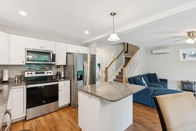 13 Junco Dr Unit 6, Windham, ME 04062 - kitchen with appliances with stainless steel finishes, a wall unit AC, open floor plan, light wood finished floors, and recessed lighting