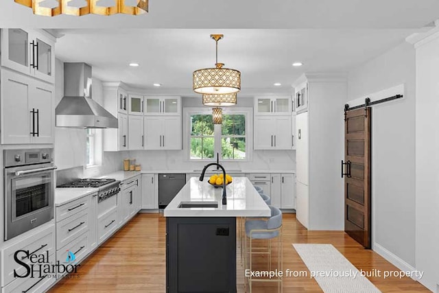 11 Clam Ln Unit B, Wells, ME 04090 - kitchen featuring appliances with stainless steel finishes, wall chimney range hood, a barn door, light countertops, and a kitchen island with sink
