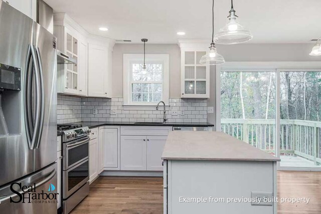 11 Clam Ln Unit B, Wells, ME 04090 - kitchen with appliances with stainless steel finishes, wood finished floors, white cabinets, decorative backsplash, and a center island