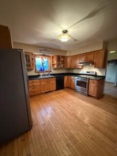 396 E Ridge Rd, Mars Hill, ME 04758 - kitchen featuring stainless steel stove, dark countertops, brown cabinetry, ceiling fan, and light wood-style floors