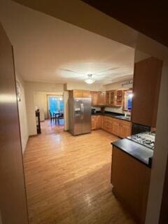 396 E Ridge Rd, Mars Hill, ME 04758 - kitchen featuring stainless steel fridge, dark countertops, brown cabinetry, and light wood finished floors