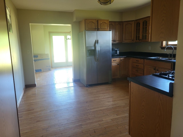 396 E Ridge Rd, Mars Hill, ME 04758 - kitchen featuring stainless steel fridge with ice dispenser, dark countertops, light wood-style floors, glass insert cabinets, and brown cabinetry
