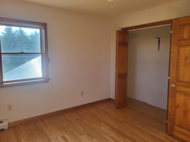 396 E Ridge Rd, Mars Hill, ME 04758 - unfurnished bedroom with multiple windows, light wood-style floors, a closet, and a baseboard radiator