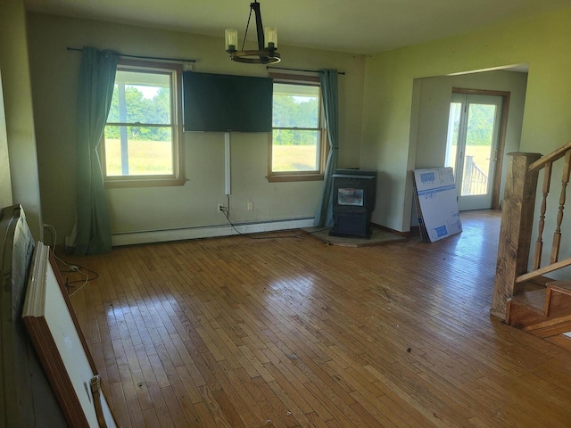 396 E Ridge Rd, Mars Hill, ME 04758 - unfurnished dining area featuring a baseboard heating unit, wood-type flooring, a wood stove, and plenty of natural light