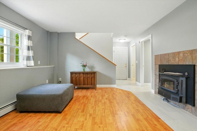 4 Hawthorne Pl, Lewiston, ME 04240 - sitting room with a baseboard radiator, light wood-type flooring, stairs, and a wood stove