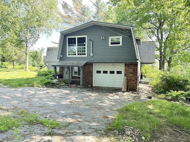 235 S Reynolds Rd, Winslow, ME 04901 - view of front of house featuring a gambrel roof, a garage, asphalt driveway, and brick siding