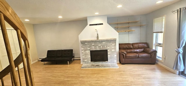 9 Hubbard Farms Rd Unit 15, Orono, ME 04473 - living area featuring light wood-style floors, a baseboard radiator, recessed lighting, a brick fireplace, and a textured ceiling