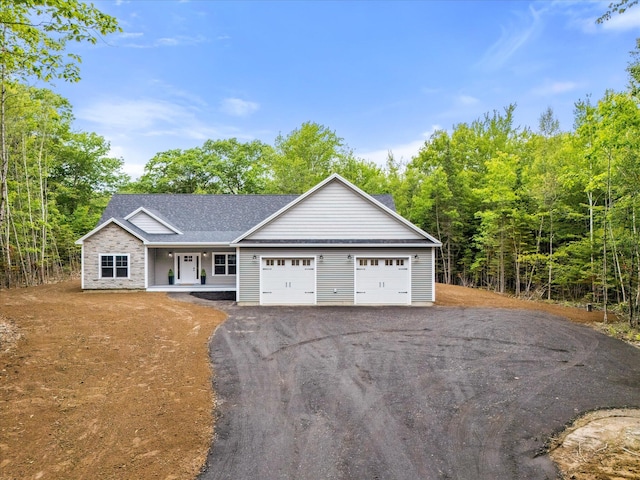18 Crestwood Dr, Orrington, ME 04474 - view of front of home featuring covered porch, a garage, a shingled roof, asphalt driveway, and stone siding