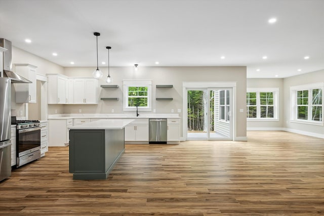 18 Crestwood Dr, Orrington, ME 04474 - kitchen with appliances with stainless steel finishes, wood finished floors, white cabinetry, wall chimney exhaust hood, and plenty of natural light