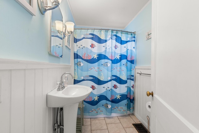 265 Nubble Rd, York, ME 03909 - bathroom with a wainscoted wall, tile patterned floors, a shower with shower curtain, crown molding, and a decorative wall