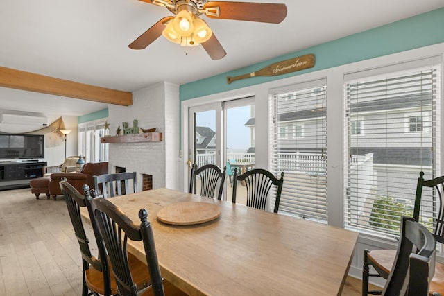 265 Nubble Rd, York, ME 03909 - dining room with a ceiling fan, wood finished floors, beam ceiling, a brick fireplace, and a wall unit AC