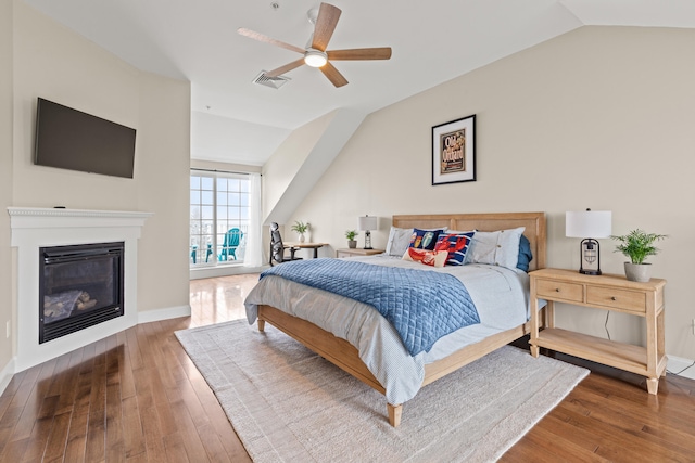 180 E Grand Ave Unit 3, Old Orchard Beach, ME 04064 - bedroom with lofted ceiling, hardwood / wood-style floors, a glass covered fireplace, and a ceiling fan