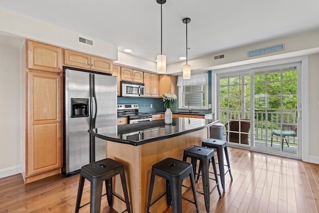 180 E Grand Ave Unit 3, Old Orchard Beach, ME 04064 - kitchen with stainless steel appliances, a breakfast bar area, light wood-type flooring, a kitchen island, and light brown cabinets
