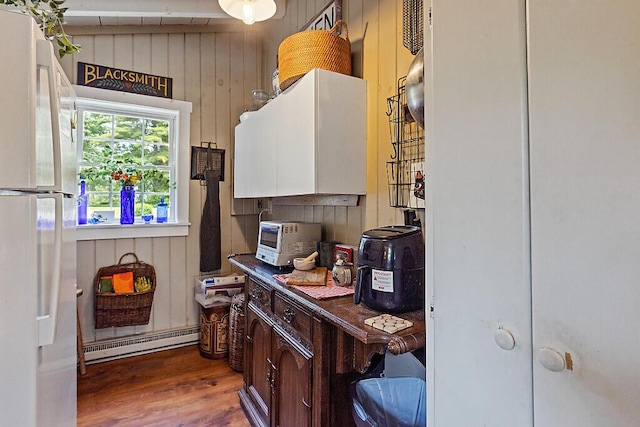 75 Spaulding Point Rd, Belgrade, ME 04917 - kitchen featuring freestanding refrigerator, a baseboard heating unit, wood finished floors, and wooden walls
