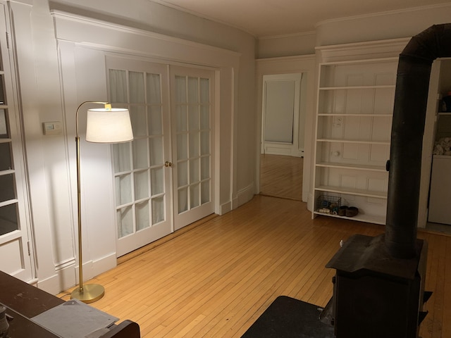 11 Gardner Ave, Machias, ME 04654 - unfurnished living room featuring wood-type flooring, crown molding, a wood stove, and french doors
