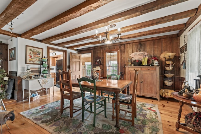 507 Ford Quint Rd, North Berwick, ME 03906 - dining room with beamed ceiling, a chandelier, wooden walls, and light wood-type flooring