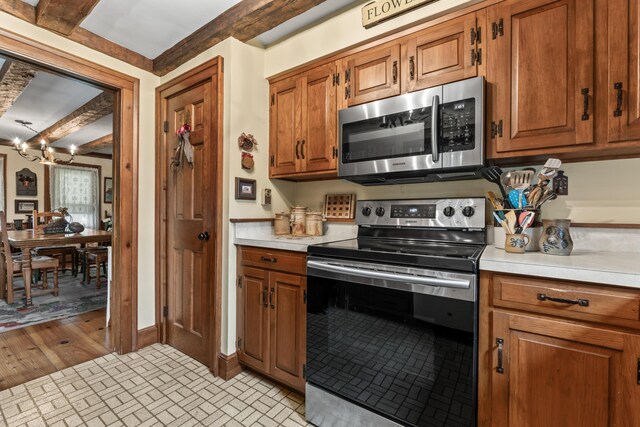 507 Ford Quint Rd, North Berwick, ME 03906 - kitchen featuring appliances with stainless steel finishes, light countertops, brown cabinetry, and a chandelier